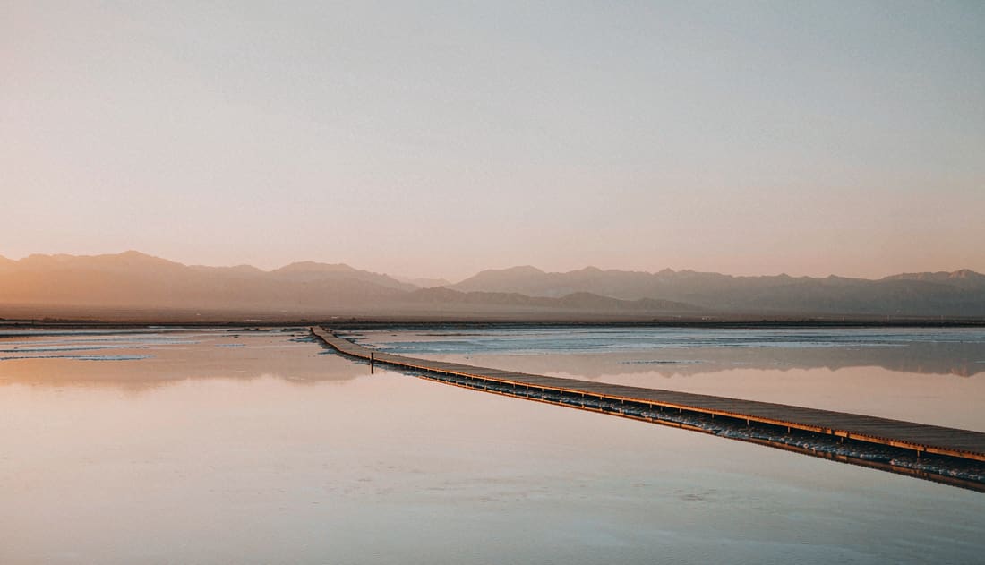 Amanecer en el salar de Chaka con el cielo reflejado en la lámina de agua y una pasarela de madera