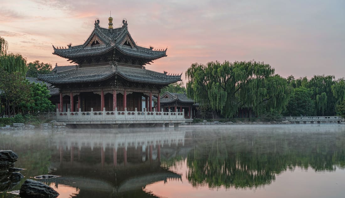Pabellón tradicional chino reflejado en un lago tranquilo al atardecer