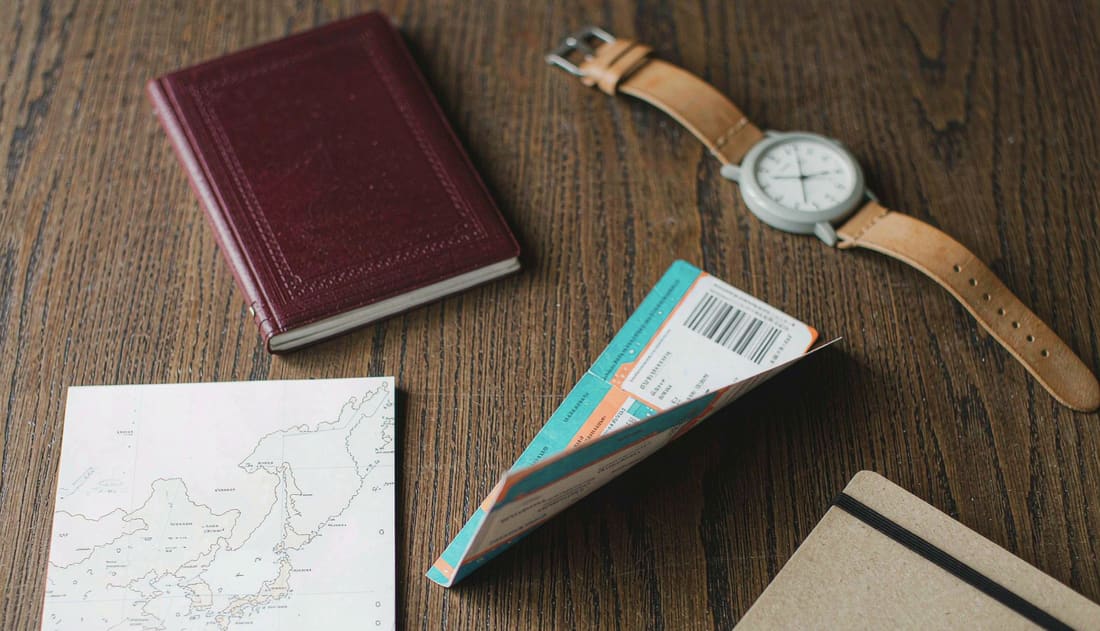 Pasaporte, tarjeta de embarque y documentación de viaje sobre una mesa de madera